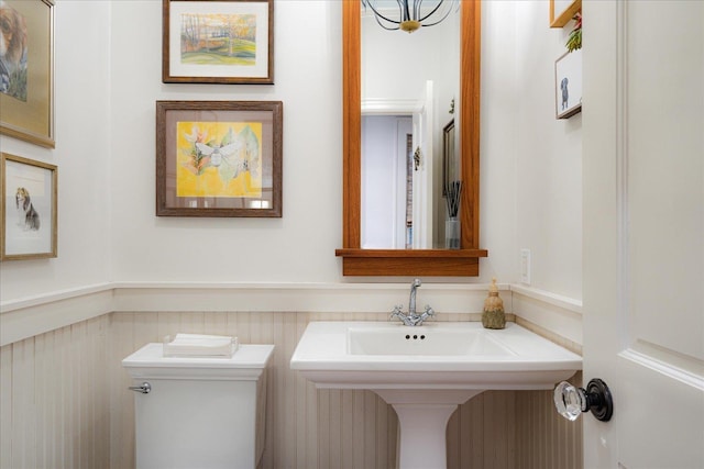 half bath with a wainscoted wall and toilet