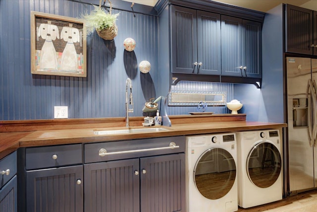washroom with wood finished floors, a sink, cabinet space, and washing machine and dryer
