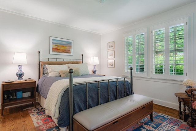 bedroom featuring baseboards, ornamental molding, and wood finished floors