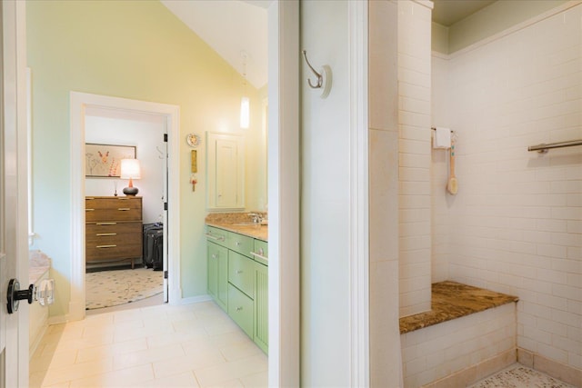 bathroom featuring vanity, tile patterned flooring, vaulted ceiling, and tiled shower