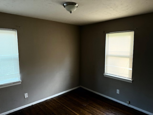 empty room featuring baseboards and dark wood-style floors