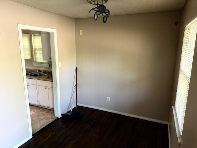 unfurnished dining area featuring baseboards, ceiling fan, dark wood-style floors, and a sink