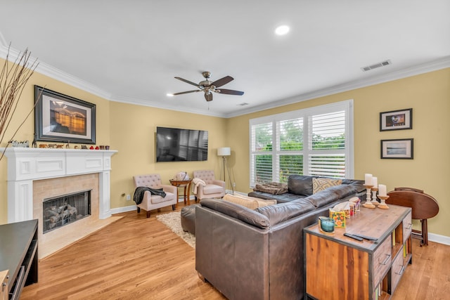living room featuring ceiling fan, visible vents, crown molding, baseboards, and light wood-style floors