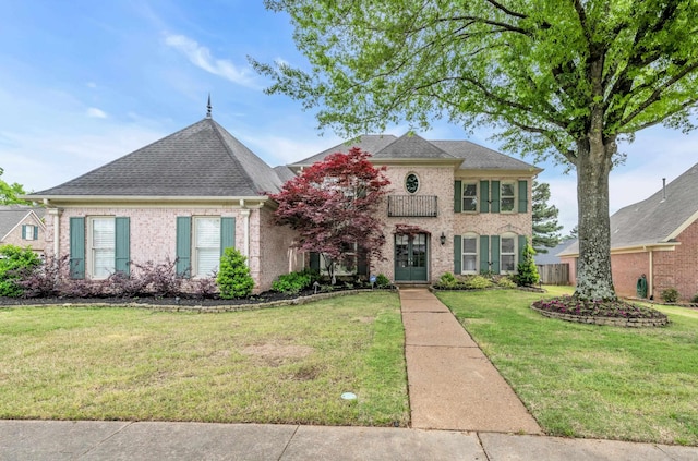 french country home featuring brick siding, a shingled roof, and a front yard