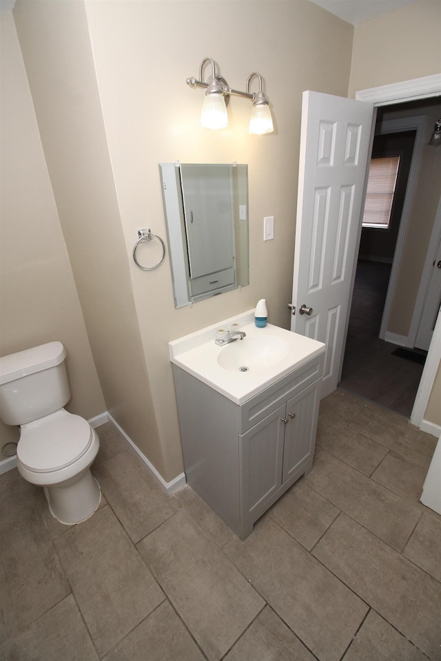 bathroom with vanity, baseboards, tile patterned flooring, and toilet