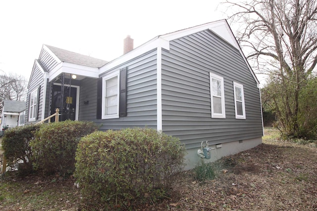 view of side of home with crawl space and a chimney