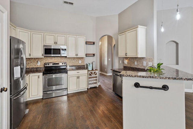 5376 Scarlet Ridge Dr, Arlington, TN 38002 - kitchen with visible vents, a peninsula, cream cabinetry, arched walkways, and appliances with stainless steel finishes