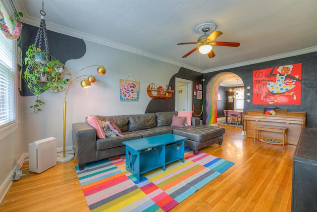 living room with a ceiling fan, arched walkways, wood finished floors, baseboards, and ornamental molding