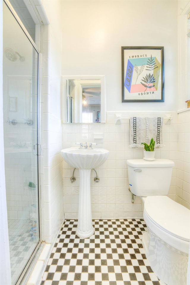 bathroom featuring toilet, tile walls, and a stall shower