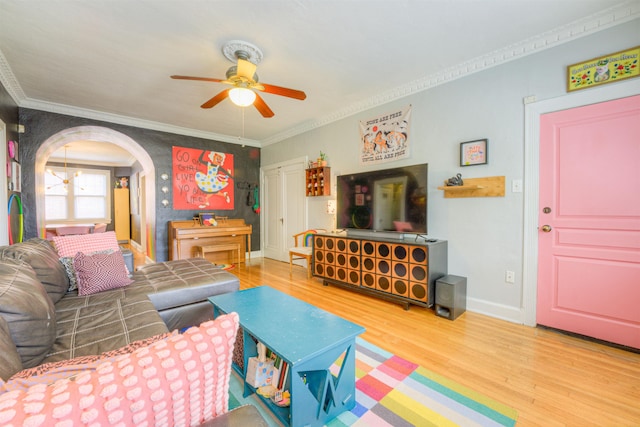 living area featuring crown molding, wood finished floors, baseboards, arched walkways, and a ceiling fan