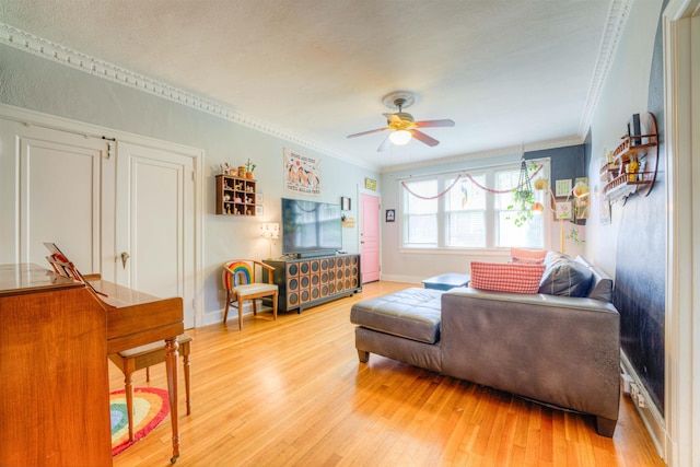 living room featuring baseboards, ornamental molding, a ceiling fan, and light wood-type flooring