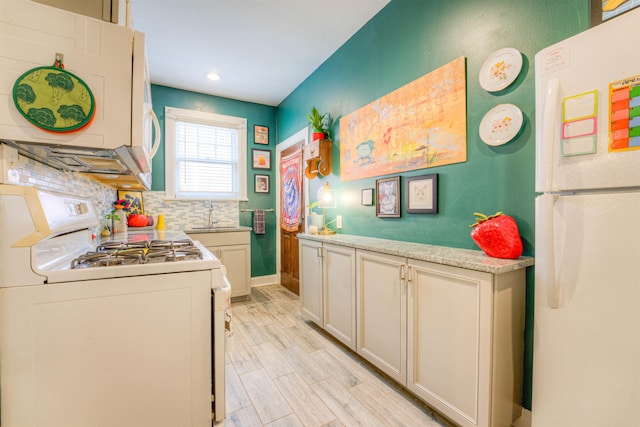 kitchen with a sink, white appliances, light countertops, recessed lighting, and tasteful backsplash