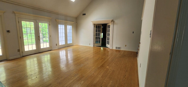 empty room featuring visible vents, wood finished floors, high vaulted ceiling, and french doors