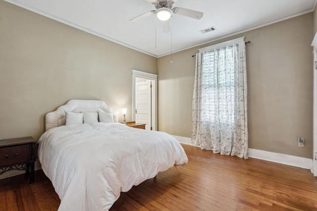 bedroom with ceiling fan, visible vents, baseboards, ornamental molding, and hardwood / wood-style floors