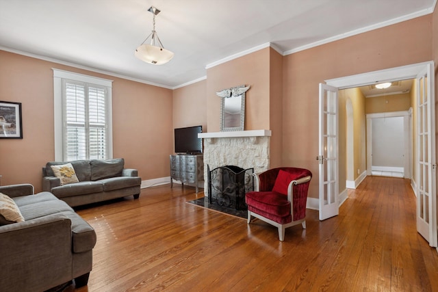 living area featuring wood-type flooring, ornamental molding, and baseboards
