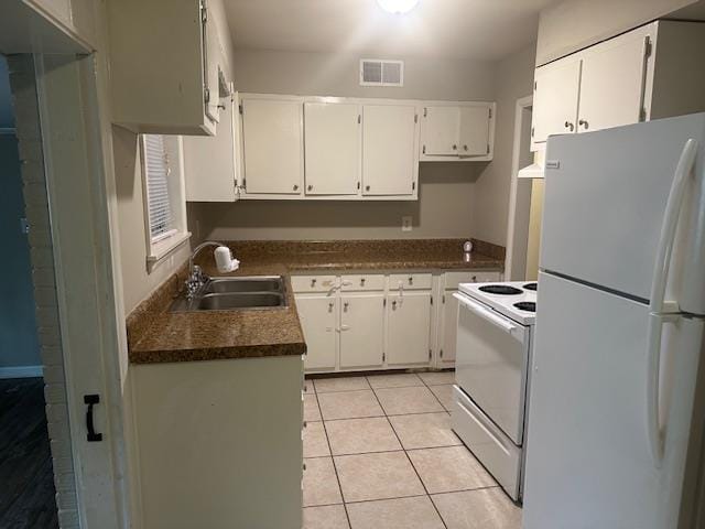 kitchen featuring visible vents, dark countertops, a sink, white appliances, and white cabinetry