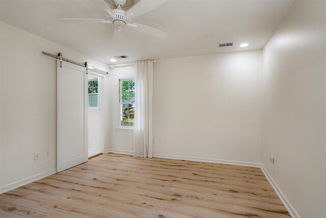 spare room with visible vents, a barn door, and light wood-type flooring