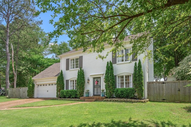 colonial inspired home with fence, an attached garage, concrete driveway, and a front yard