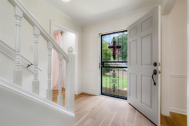 foyer entrance with baseboards, ornamental molding, stairs, and wood finished floors