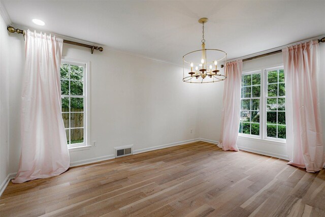 unfurnished dining area with baseboards, a notable chandelier, light wood finished floors, and visible vents