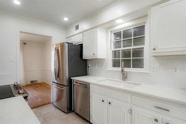 kitchen with a sink, stainless steel appliances, white cabinetry, and visible vents