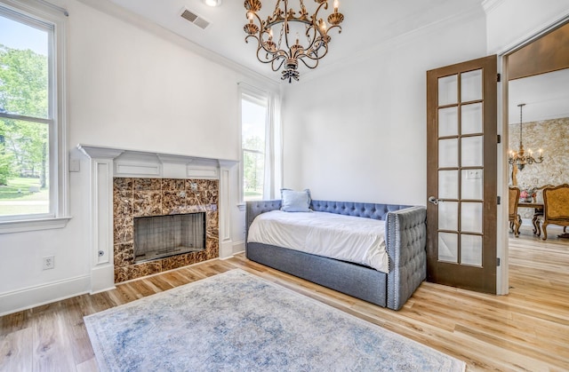 bedroom with visible vents, a fireplace, wood finished floors, a chandelier, and ornamental molding