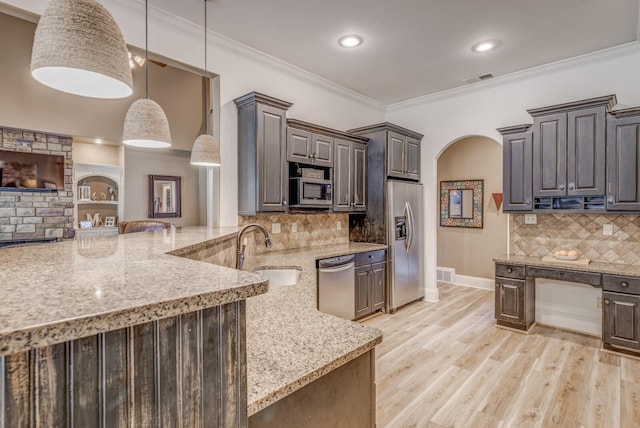 kitchen featuring appliances with stainless steel finishes, light stone counters, a sink, arched walkways, and visible vents