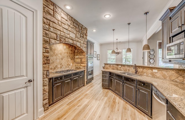 kitchen with tasteful backsplash, a sink, light wood-style floors, ornamental molding, and stainless steel appliances