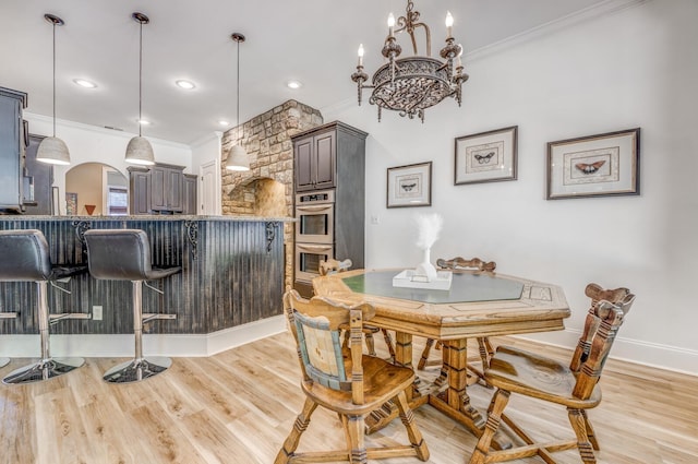 dining room featuring crown molding, light wood-style floors, baseboards, and a notable chandelier