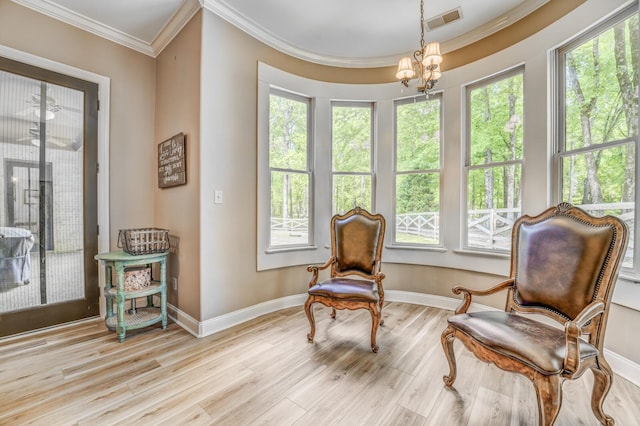 living area with visible vents, crown molding, wood finished floors, baseboards, and a notable chandelier