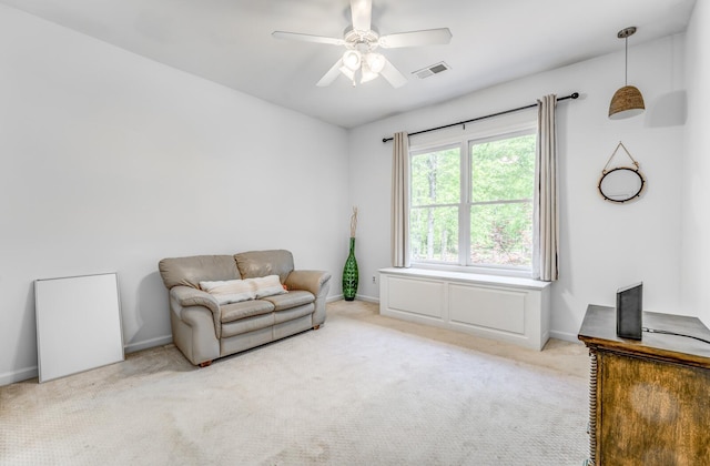 living area with visible vents, a ceiling fan, baseboards, and light colored carpet
