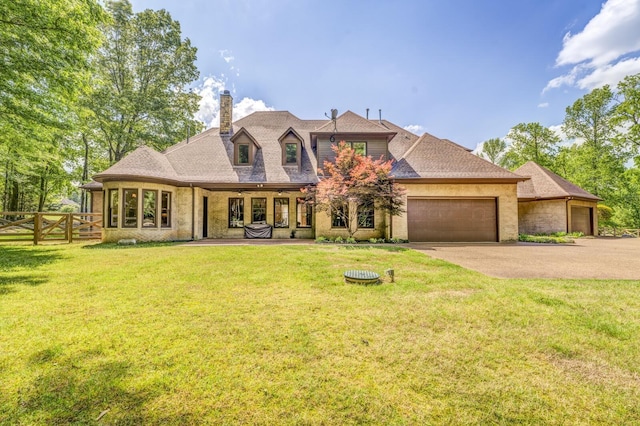 french country style house with a garage, a front lawn, fence, a chimney, and concrete driveway