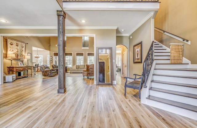entryway featuring crown molding, stairs, recessed lighting, light wood-type flooring, and arched walkways