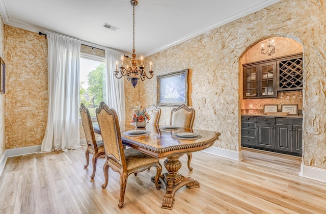dining area with visible vents, crown molding, an inviting chandelier, baseboards, and light wood-type flooring