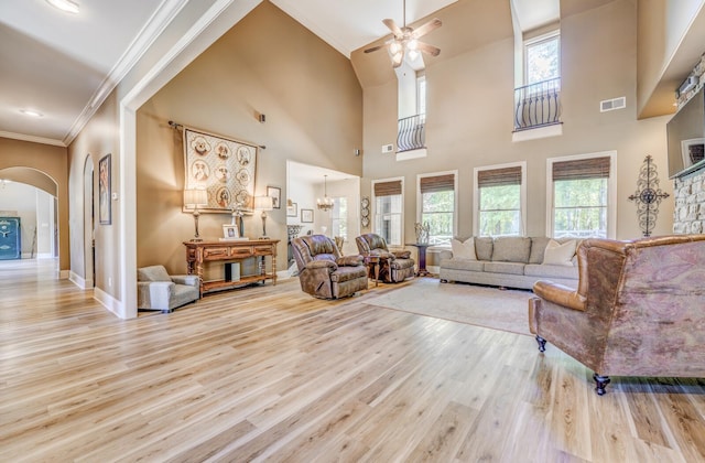 living area with ceiling fan, arched walkways, wood finished floors, baseboards, and ornamental molding