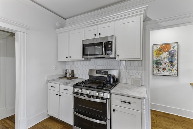 kitchen with decorative backsplash, baseboards, dark wood-style floors, stainless steel appliances, and white cabinetry