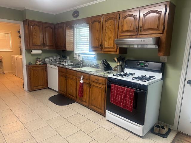 kitchen featuring crown molding, gas range oven, under cabinet range hood, washing machine and clothes dryer, and dishwasher