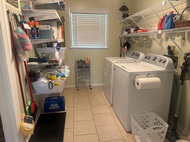 washroom with light tile patterned floors, baseboards, laundry area, and washer and clothes dryer