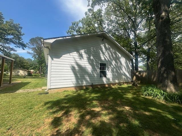 view of property exterior with a lawn and fence