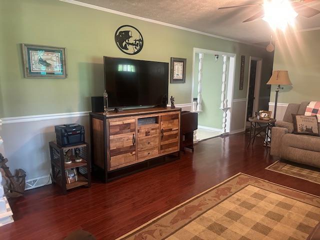 living room featuring crown molding, a ceiling fan, baseboards, and wood finished floors