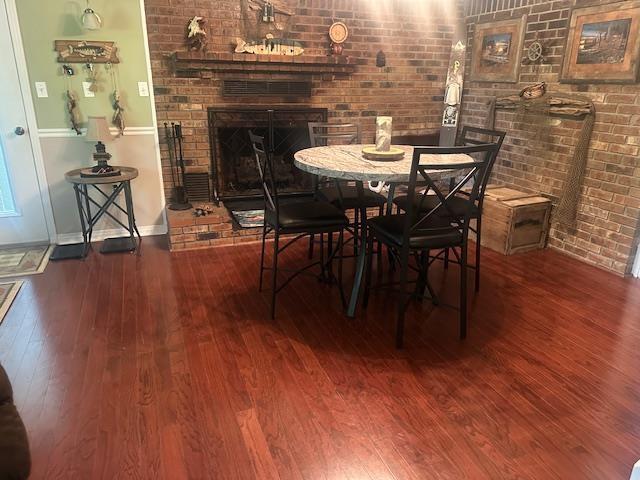 dining space featuring baseboards, brick wall, and hardwood / wood-style floors