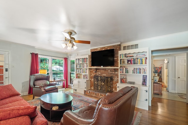 living room with crown molding, a ceiling fan, wood finished floors, and a fireplace
