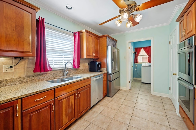 kitchen featuring a ceiling fan, backsplash, appliances with stainless steel finishes, a sink, and washer / dryer
