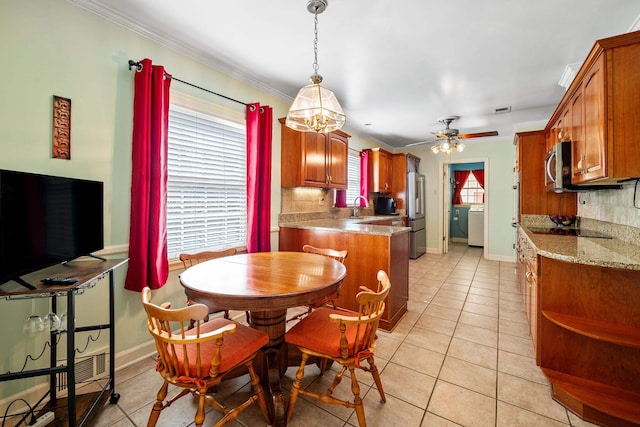 dining room with crown molding, ceiling fan with notable chandelier, washer / clothes dryer, light tile patterned floors, and visible vents