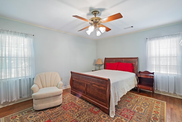 bedroom with multiple windows, a ceiling fan, wood finished floors, and visible vents