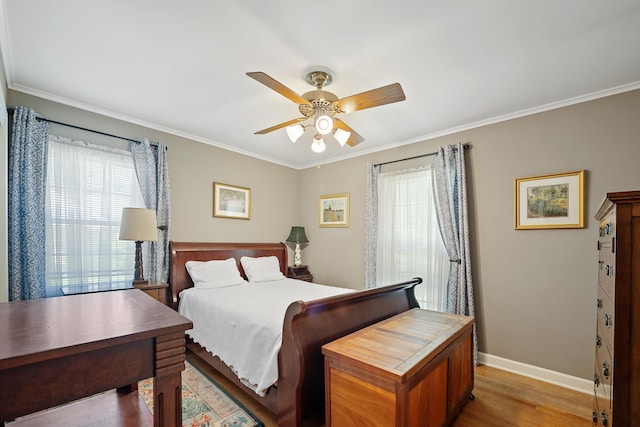 bedroom featuring baseboards, multiple windows, ornamental molding, and light wood-style flooring