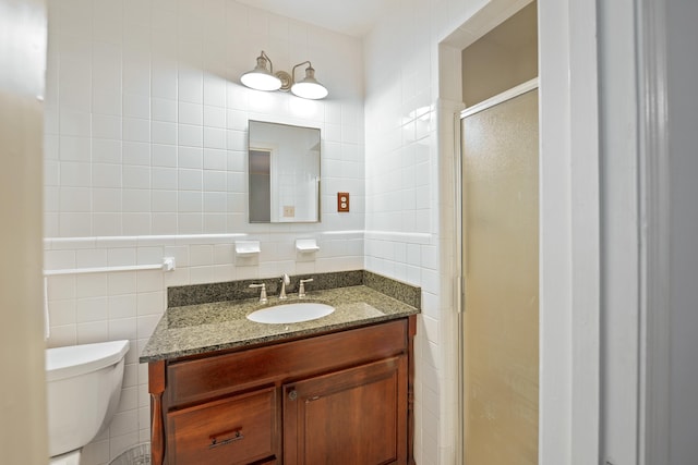 bathroom featuring vanity, a stall shower, toilet, and tile walls