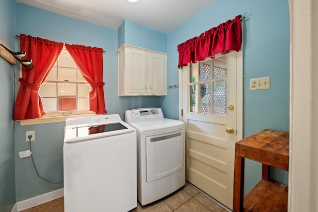 laundry area with a healthy amount of sunlight, washing machine and dryer, cabinet space, and light tile patterned flooring