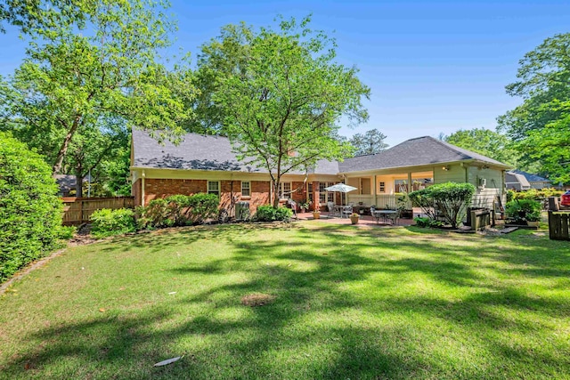 rear view of house featuring fence, a shingled roof, a yard, and a patio area