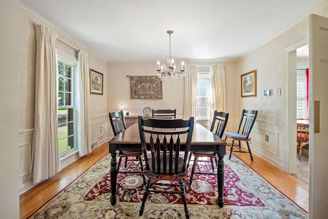 dining room with an inviting chandelier, a healthy amount of sunlight, wood finished floors, and a decorative wall